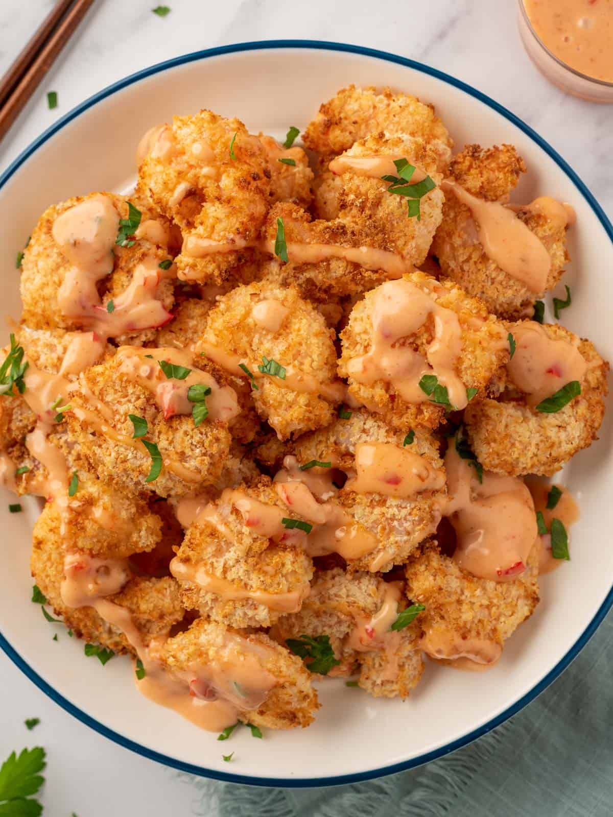 A pile of air fryer panko shrimp with bang bang sauce.