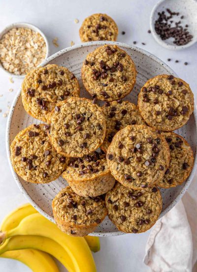 Overhead view of a plate of baked banana oatmeal cups with ingredients scattered around.