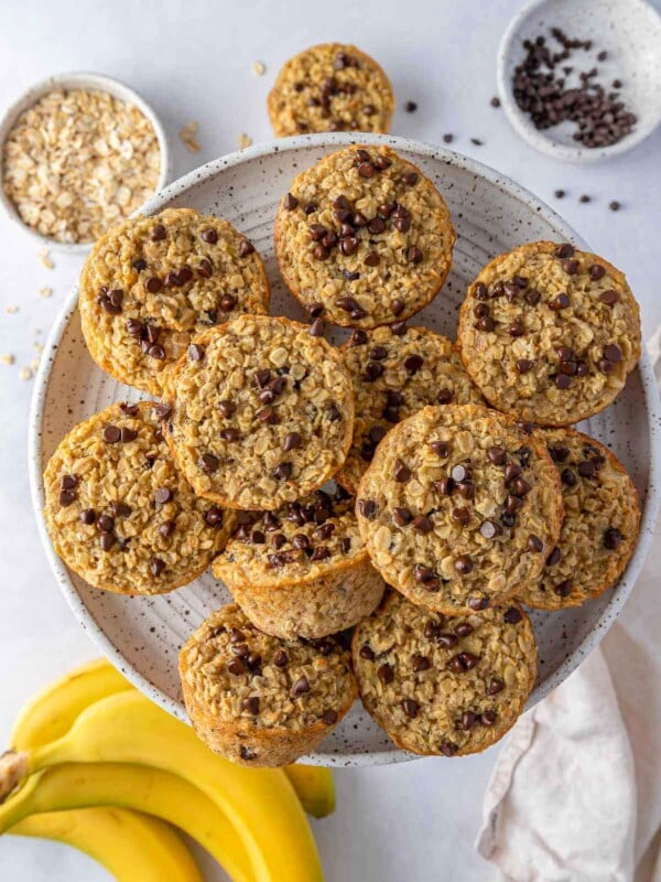 Overhead view of a plate of baked banana oatmeal cups with ingredients scattered around.