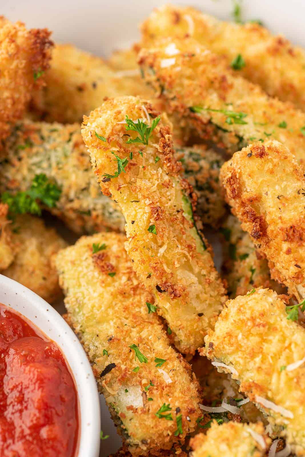 Close up of breaded zucchini fries on a platter.