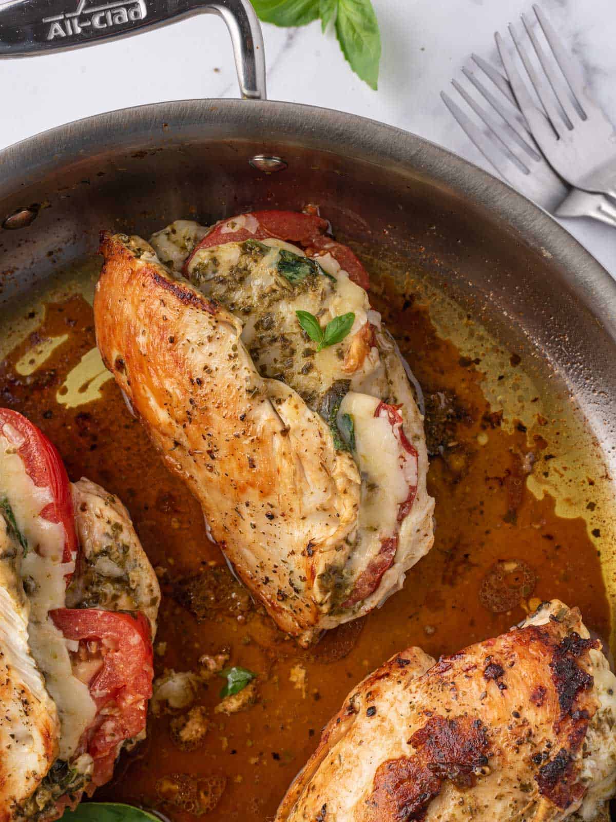Pesto stuffed chicken breast cooking in a skillet.