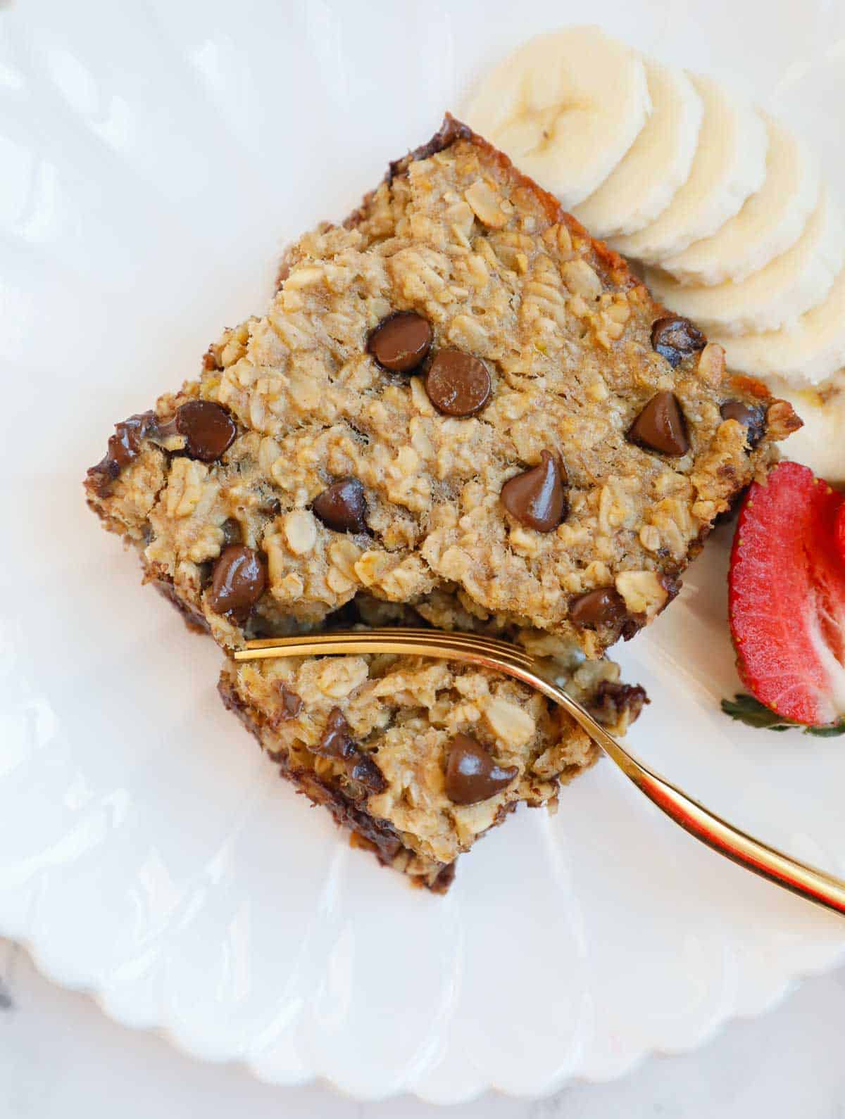 A plate with chocolate chip baked oats, fruit and a fork. 