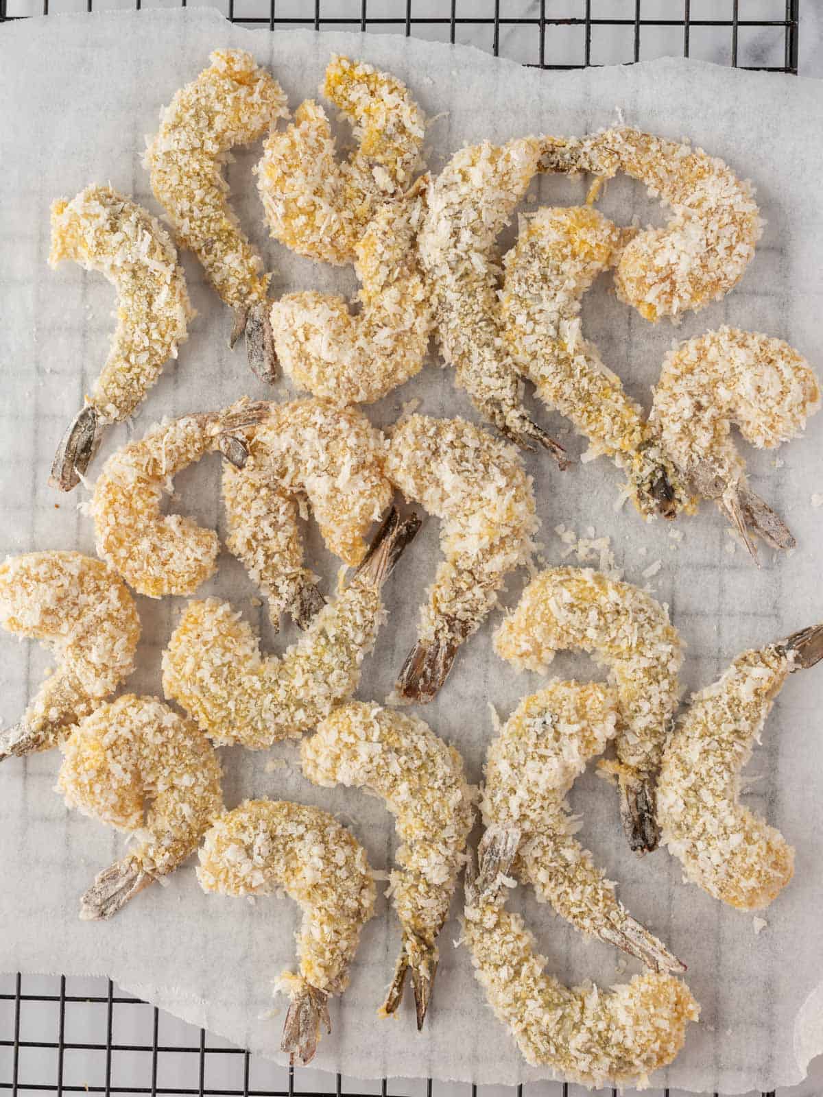 Coated shrimp resting on parchment before air frying.