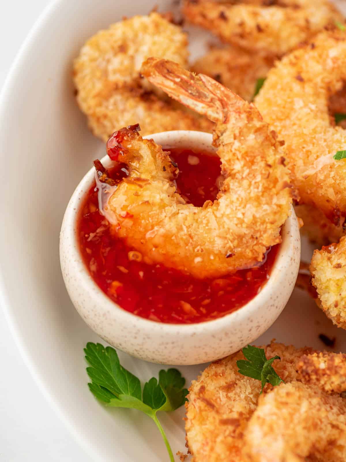 air fryer fried shrimp being dipped into sweet chili sauce.