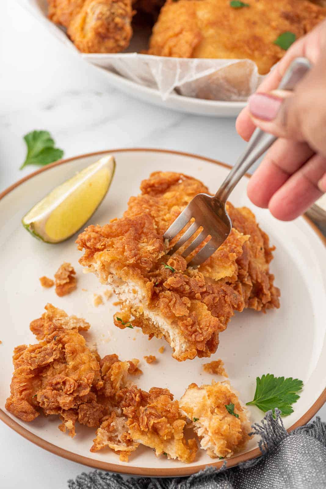 A fork holds a piece of crunchy fried chicken.