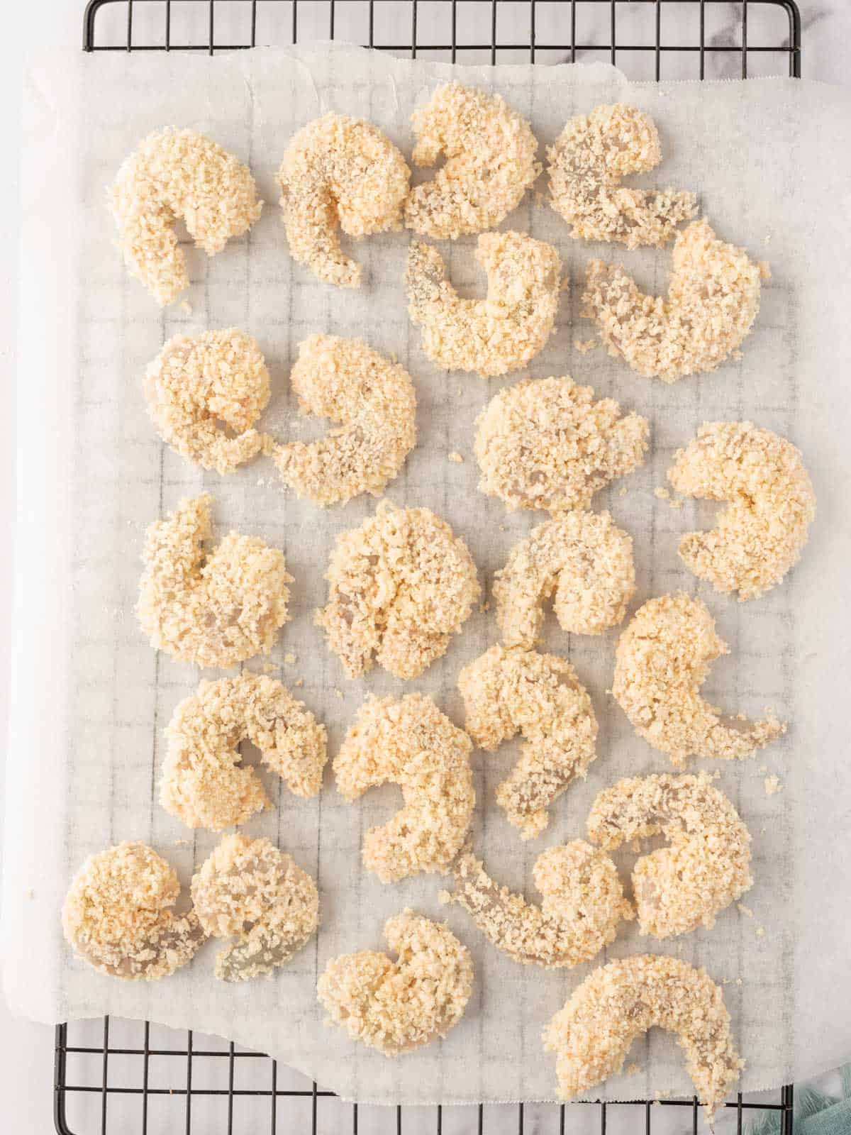 Breaded shrimp resting on parchment paper.