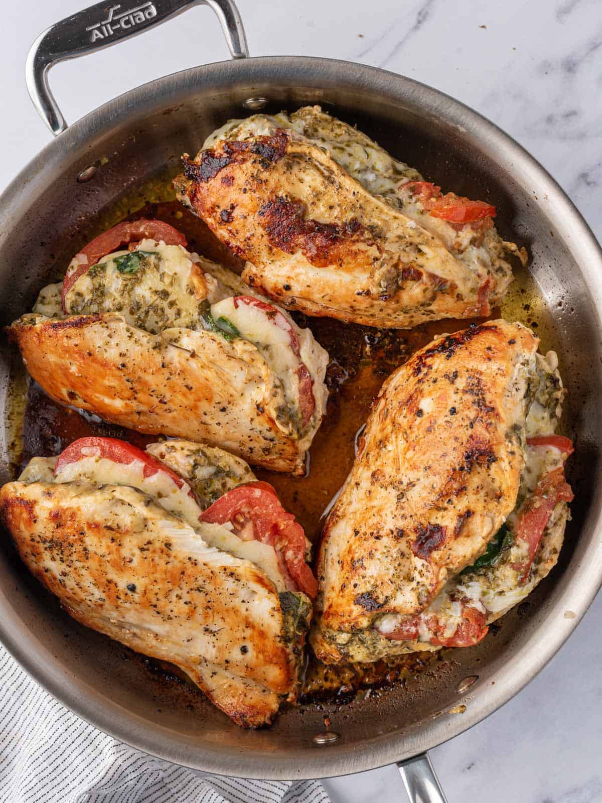 Chicken with pesto and mozzarella in a skillet.