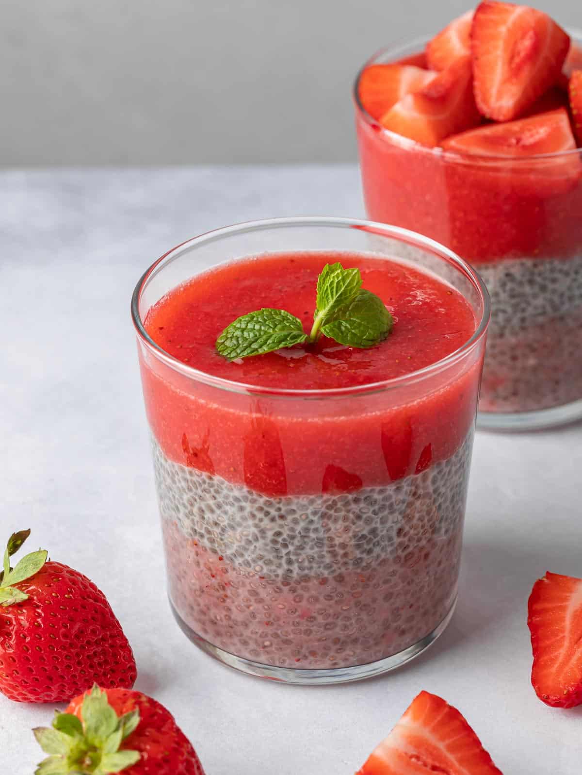 Glass of strawberry chia pudding with mint on top.