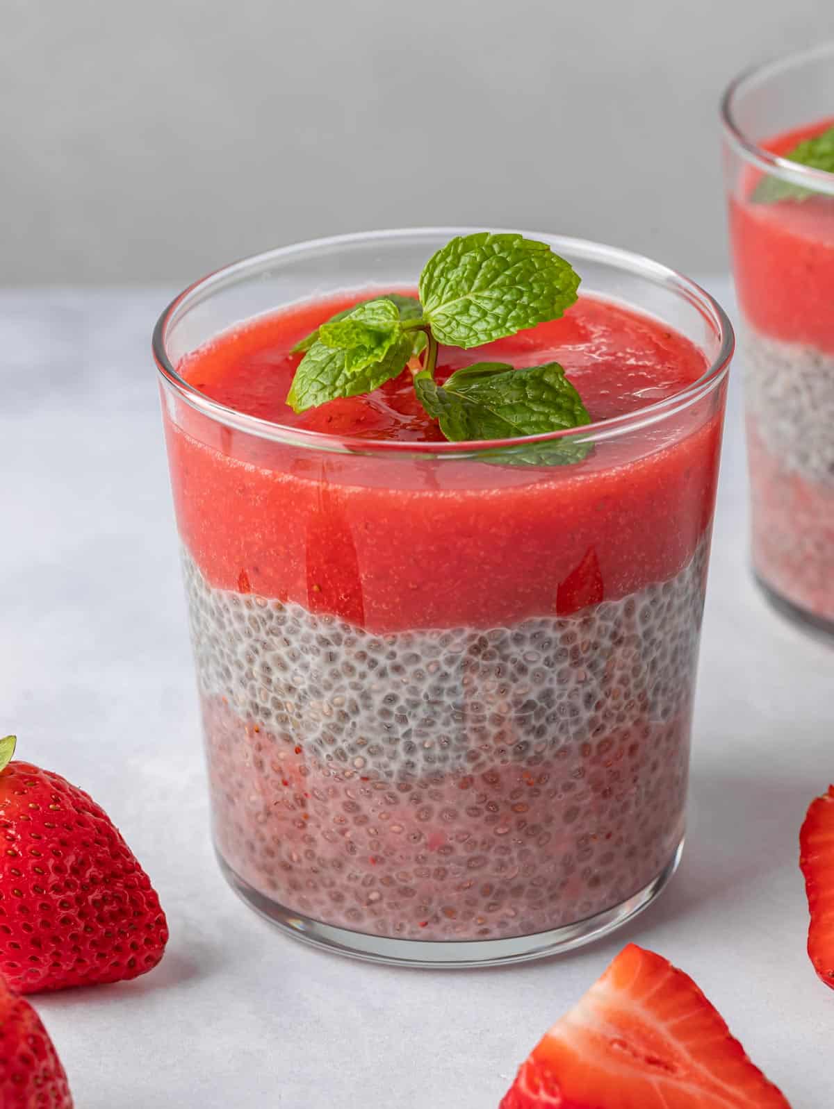A glass of strawberry chia pudding with mint on top.