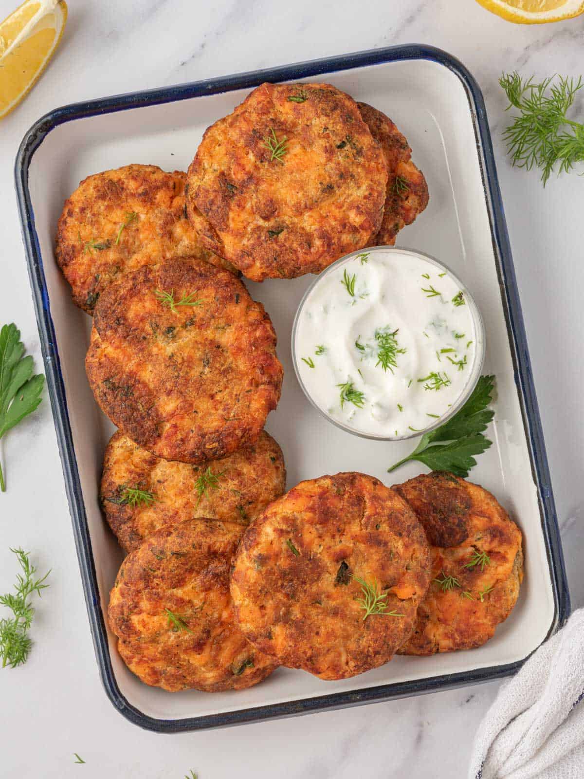 A tray of salmon corquettes air fryer with a small bowl of tzatziki sauce.