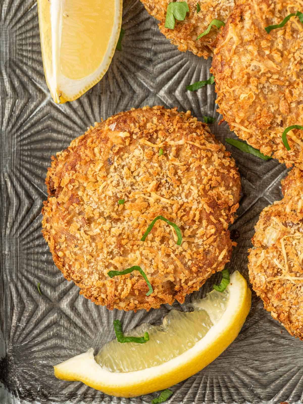 Close up of canned tuna fish cakes with lemon wedges.