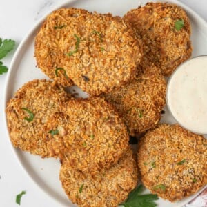 A plate with crispy tuna cakes and a dipping sauce for serving.