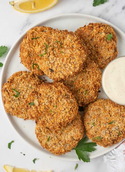 A plate with crispy tuna cakes and a dipping sauce for serving.