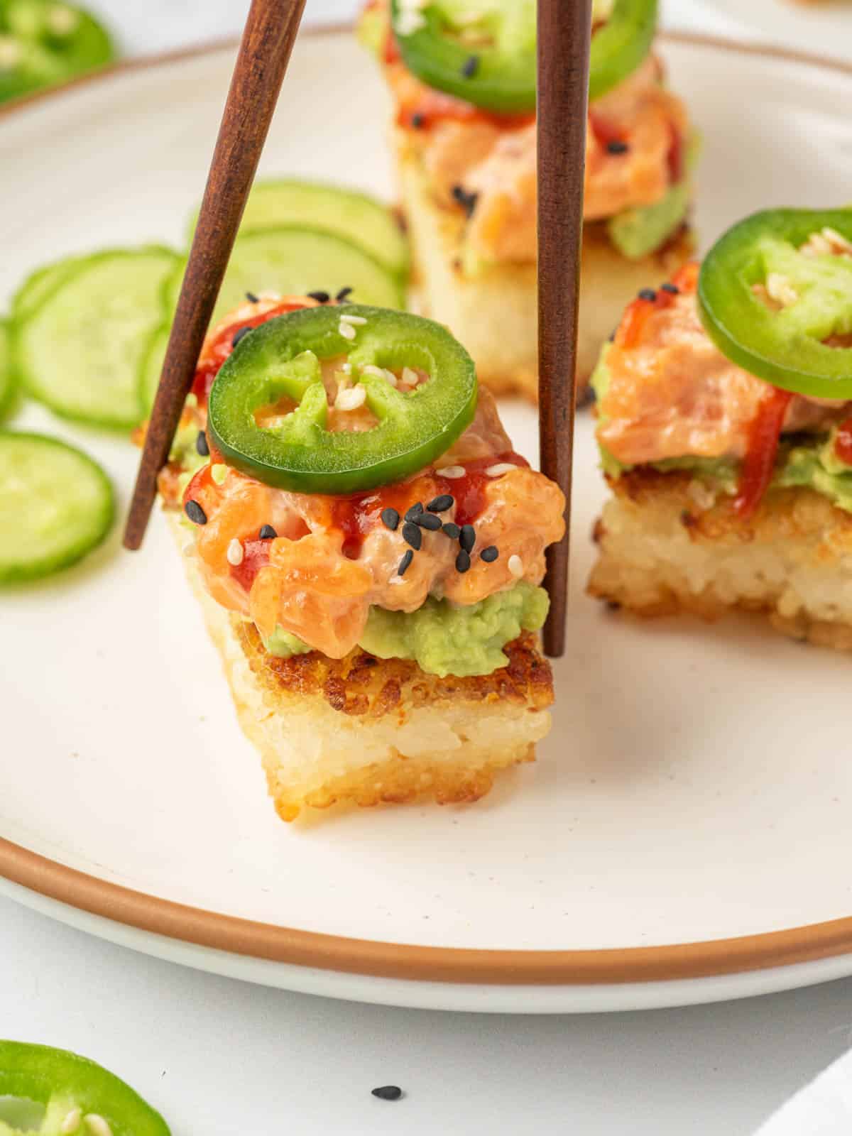 Chopsticks pick up a piece of spicy salmon crispy rice.