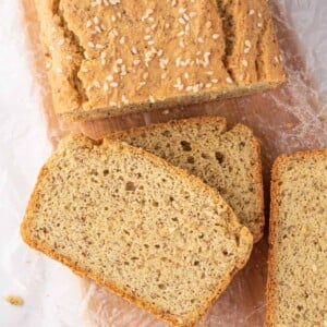 A loaf of keto sandwich bread with several slices of bread rest on a bread board.