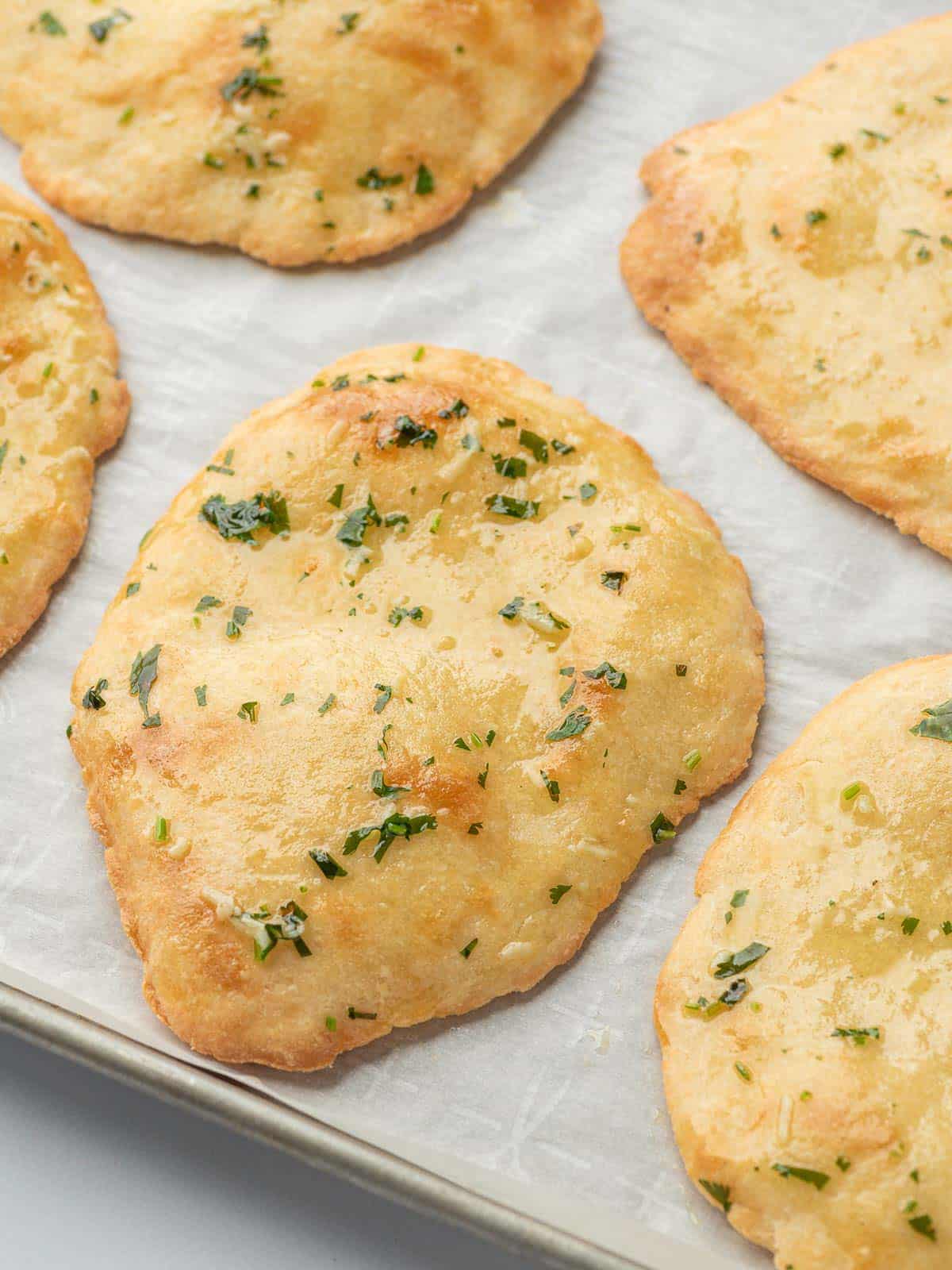 Almond flour naan on parchment on a baking tray.