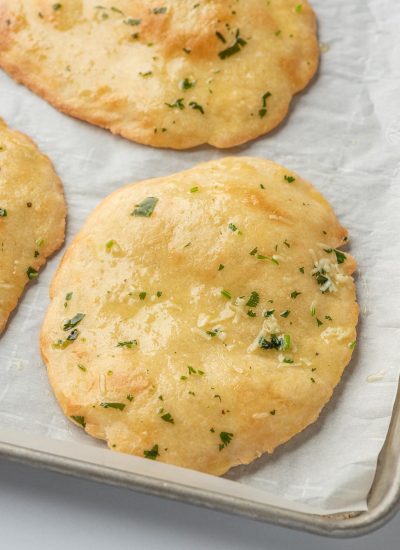 Low carb naan bread on parchment on a baking tray.