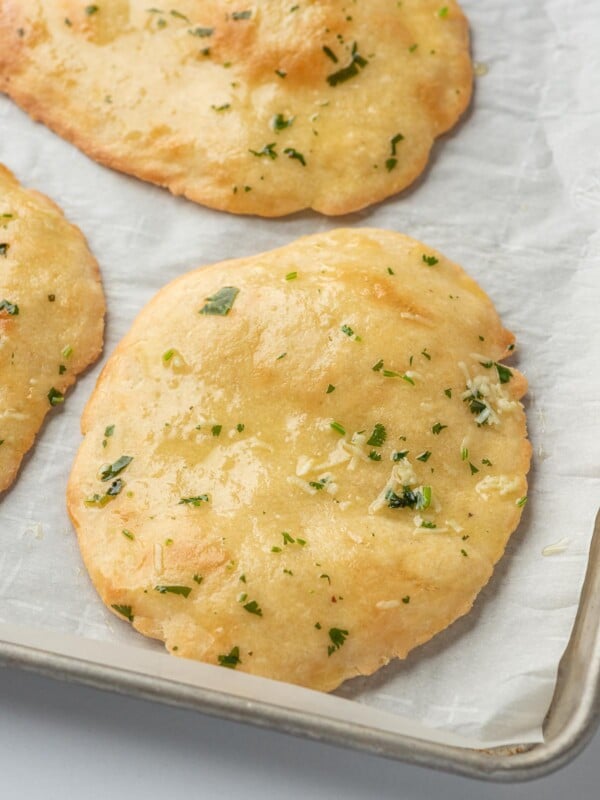 Low carb naan bread on parchment on a baking tray.