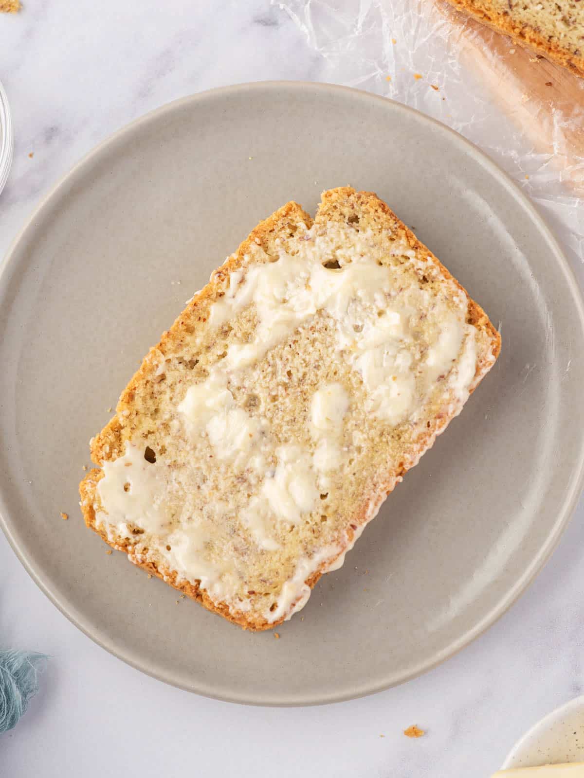 A slice of gluten free keto bread topped with melting butter sits on a grey plate.