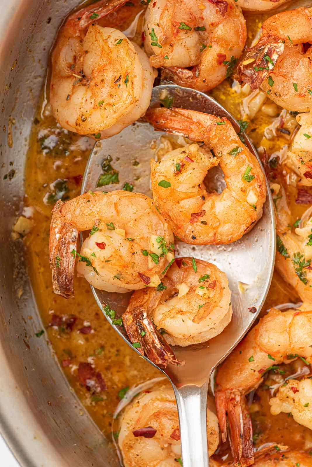 Closeup of a spoon with garlic and lemon shrimp.