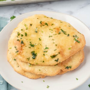 Three pieces of keto garlic naan on a white plate.