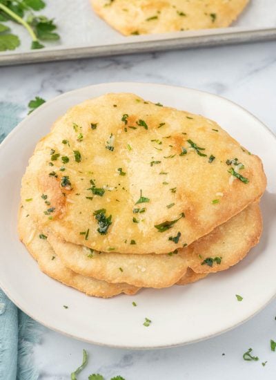 Three pieces of keto garlic naan on a white plate.
