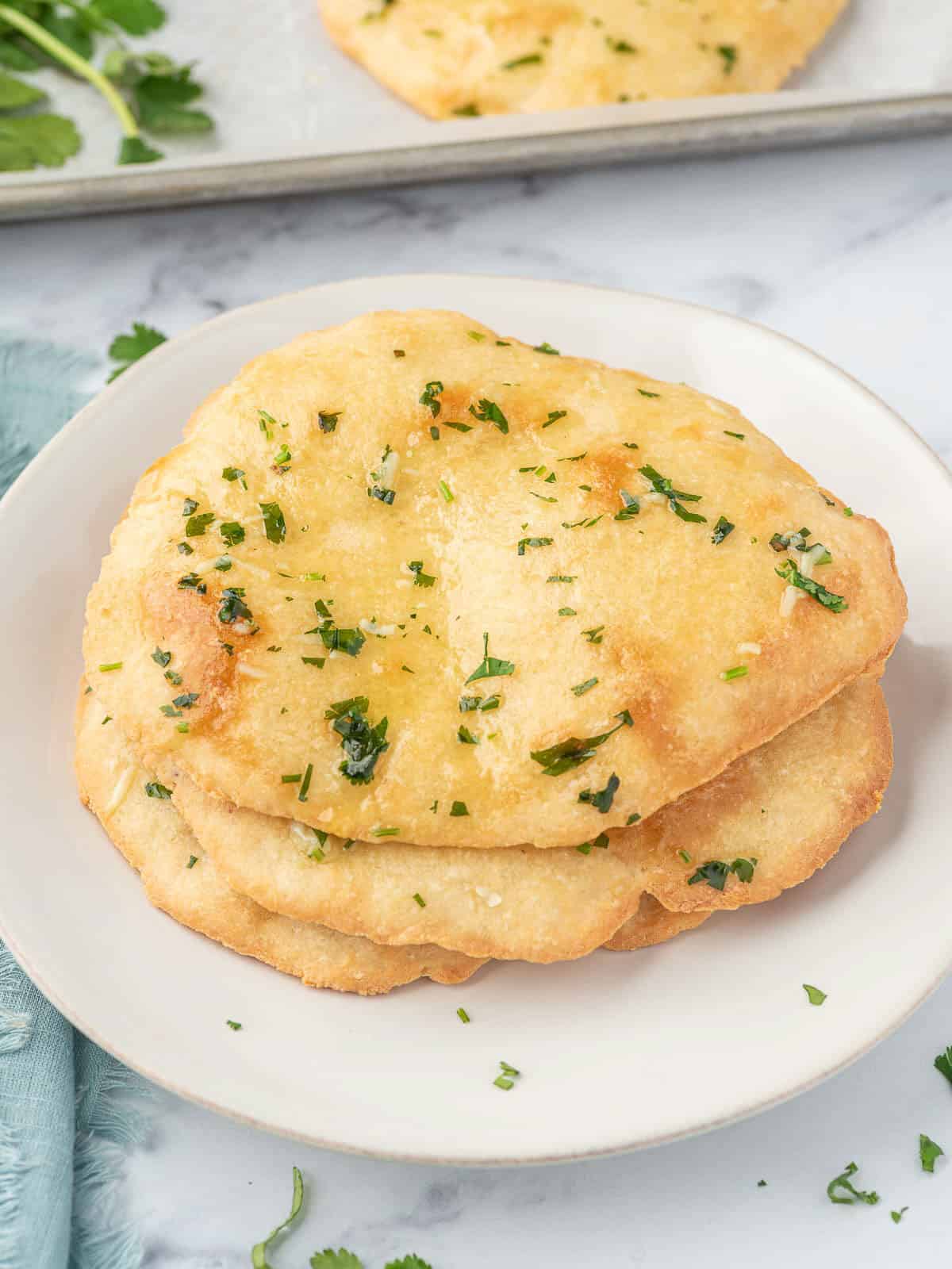 Three pieces of keto garlic naan on a white plate.