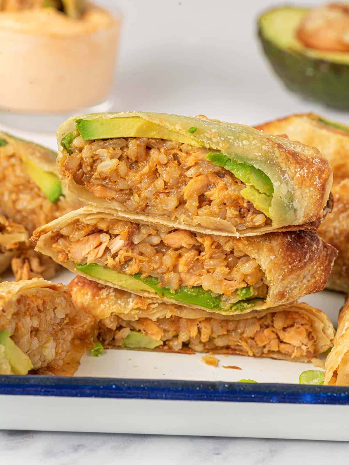 Airfried Egg Rolls cut in half and stacked on a plate.