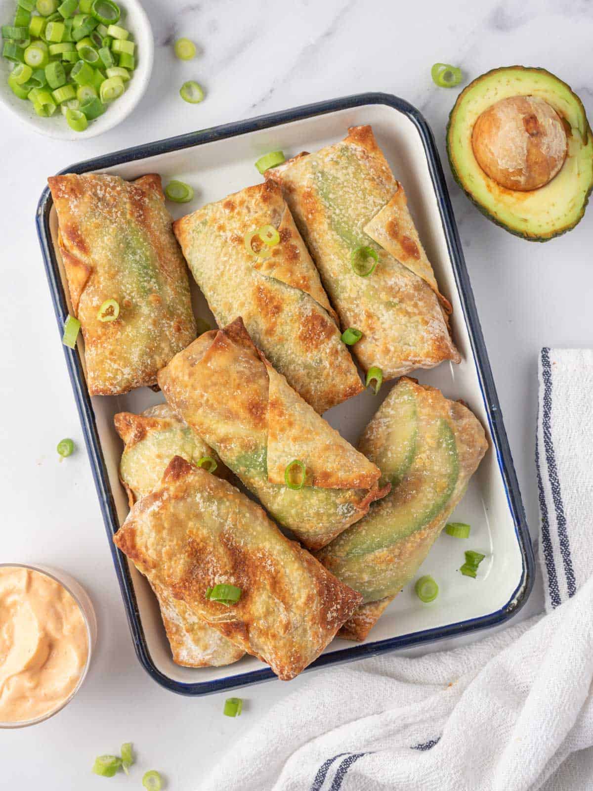 A tray of salmon egg rolls garnished with green onions.