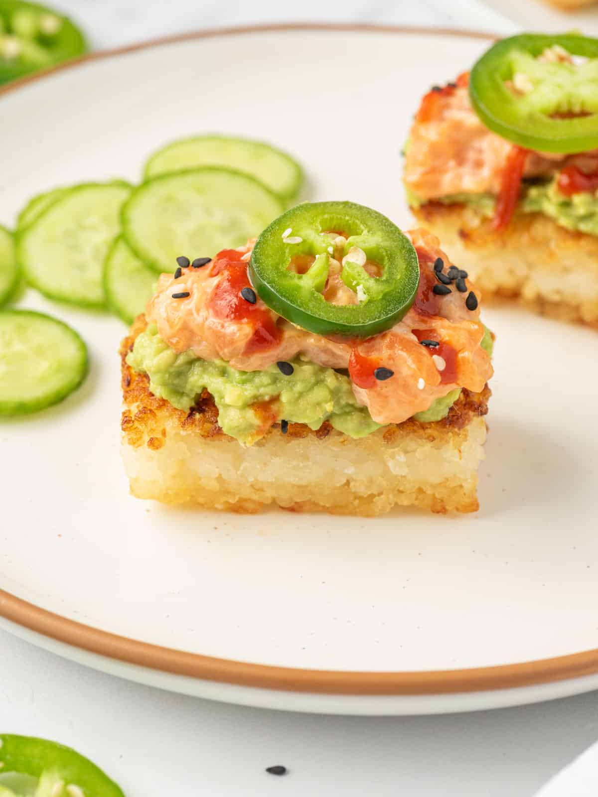 Spicy salmon crispy rice topped with jalapeno on a plate.