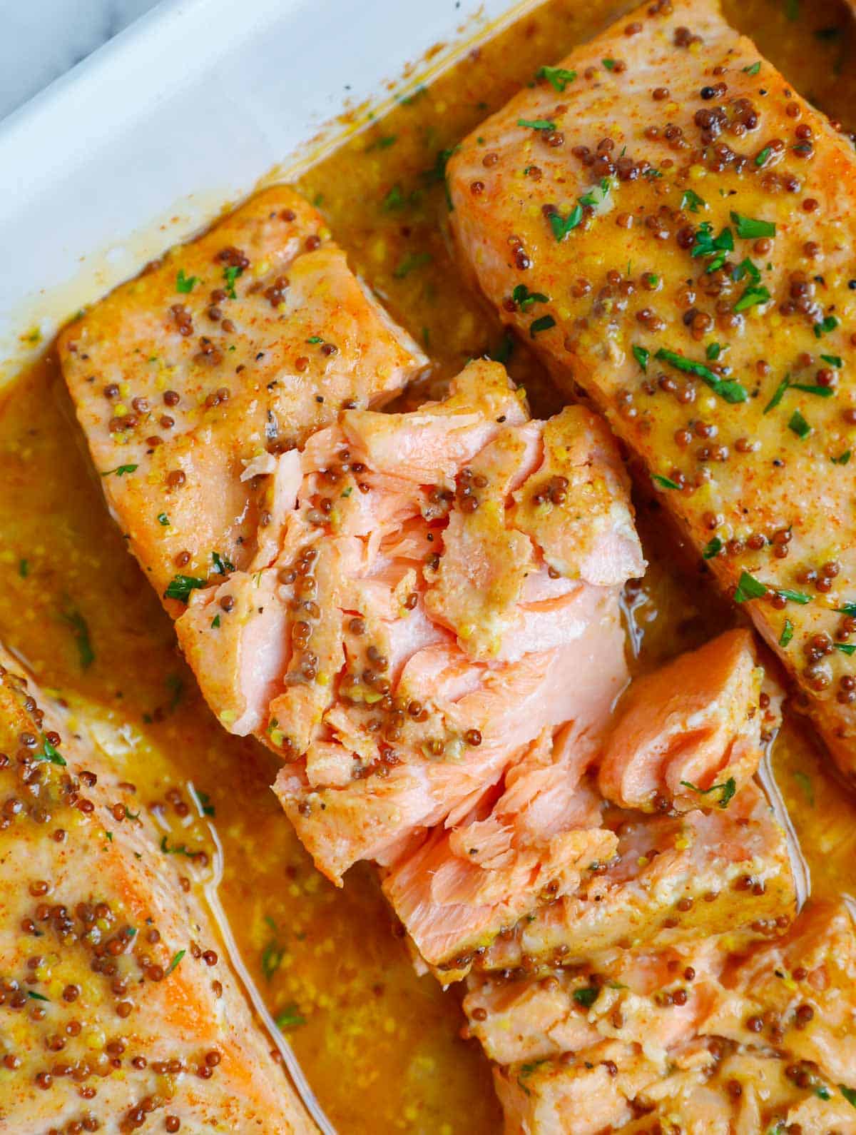 Flakey baked dijon salmon in a baking dish.