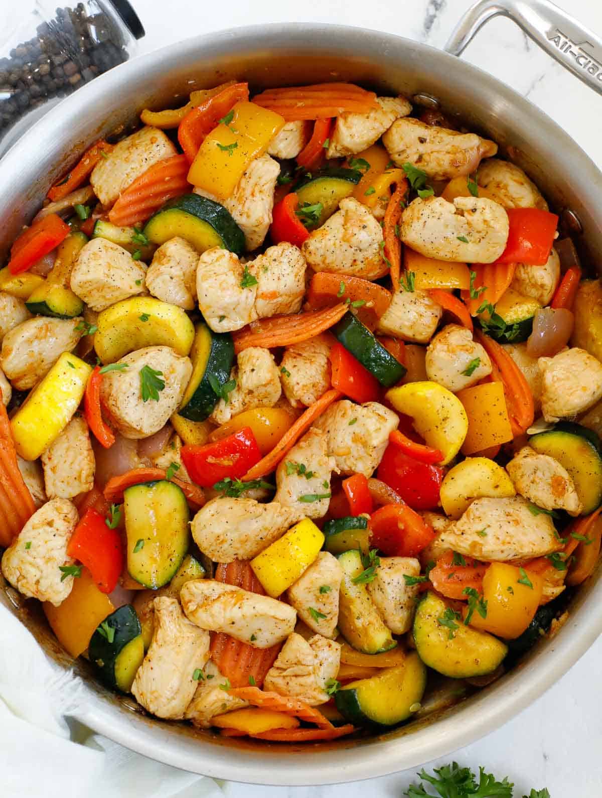 Healthy chicken and vegetable skillet topped with herbs.