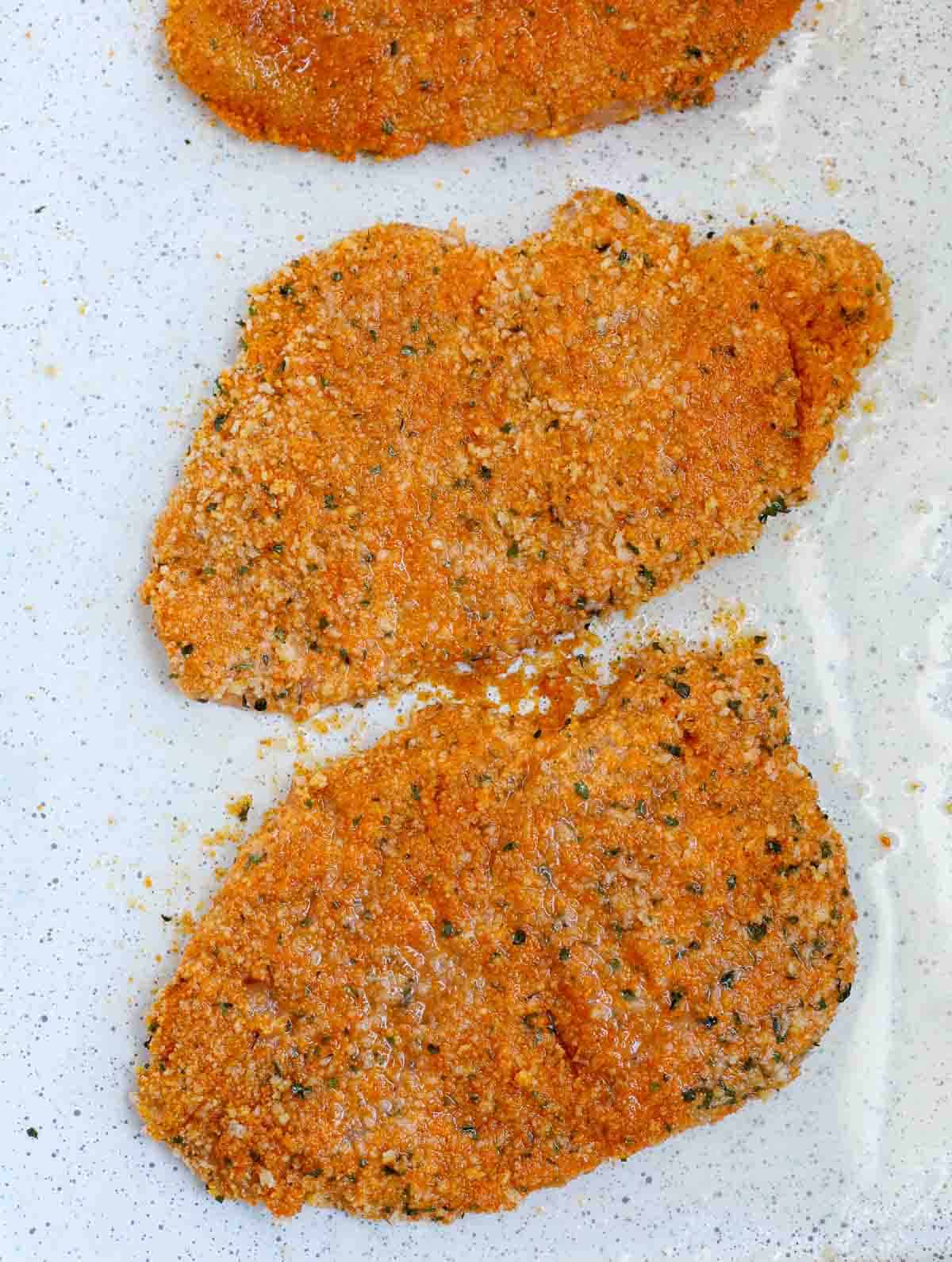 Baked chicken cutlets waiting to be garnished with parsley.