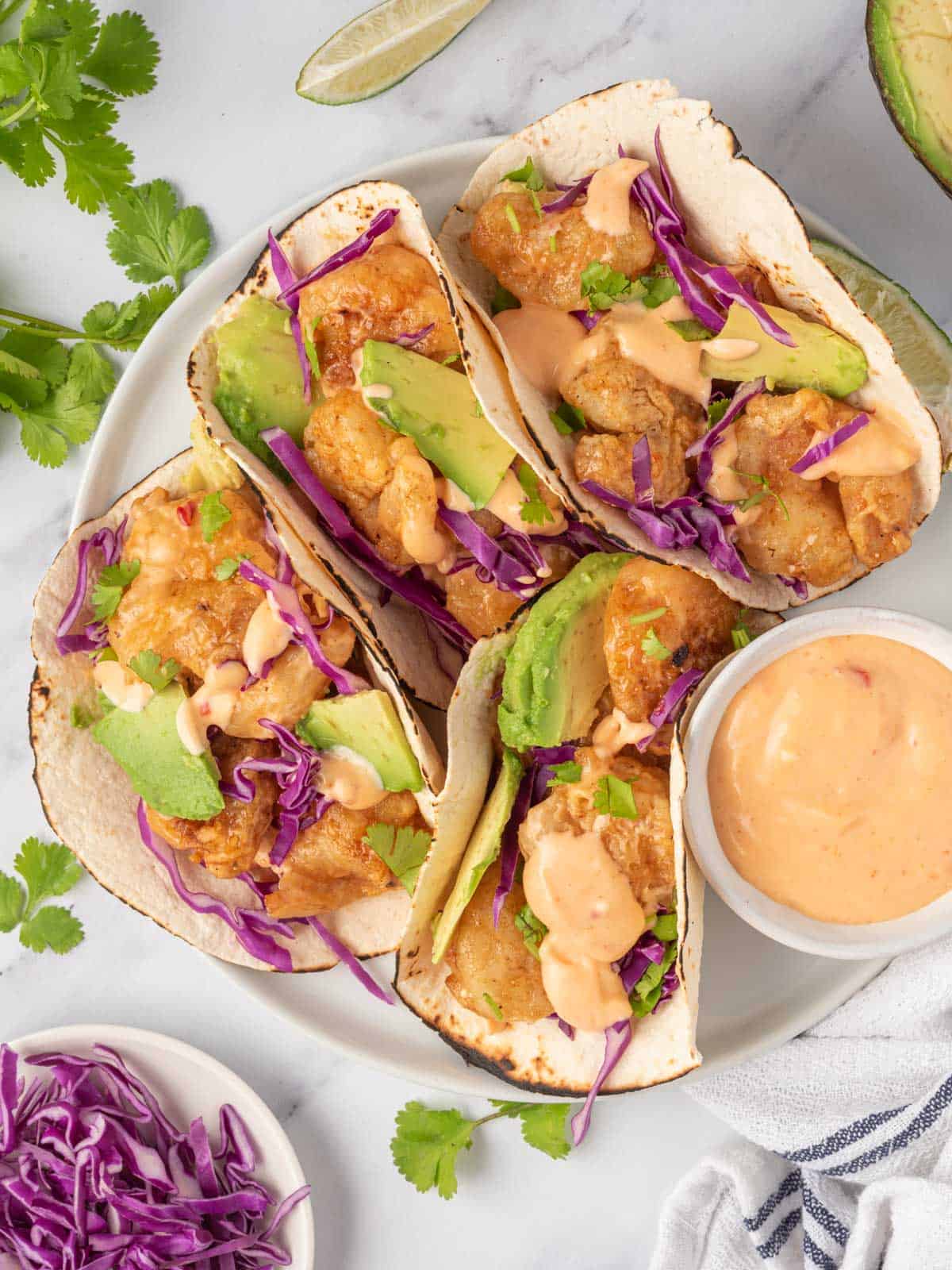 A plate of spicy shrimp tacos with dynamite sauce.