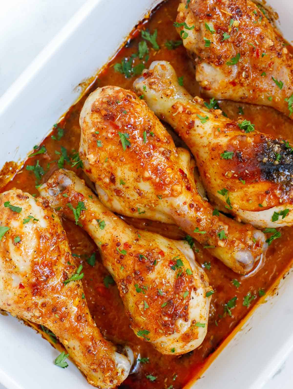 Chicken legs with honey mustard in a baking dish for serving.