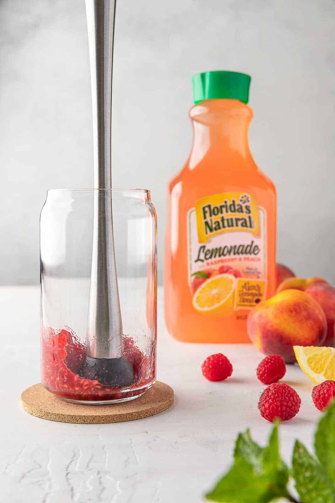 mashing the fresh raspberries in a cup