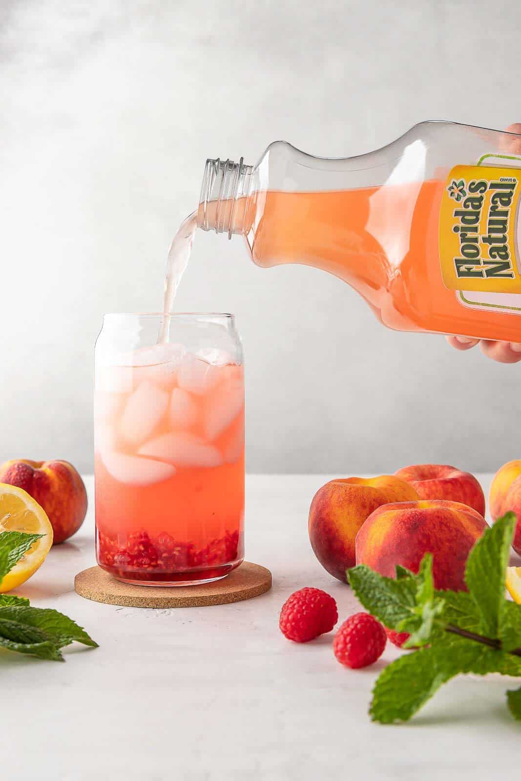 pouring raspberry lemonade in a cup filled with ice