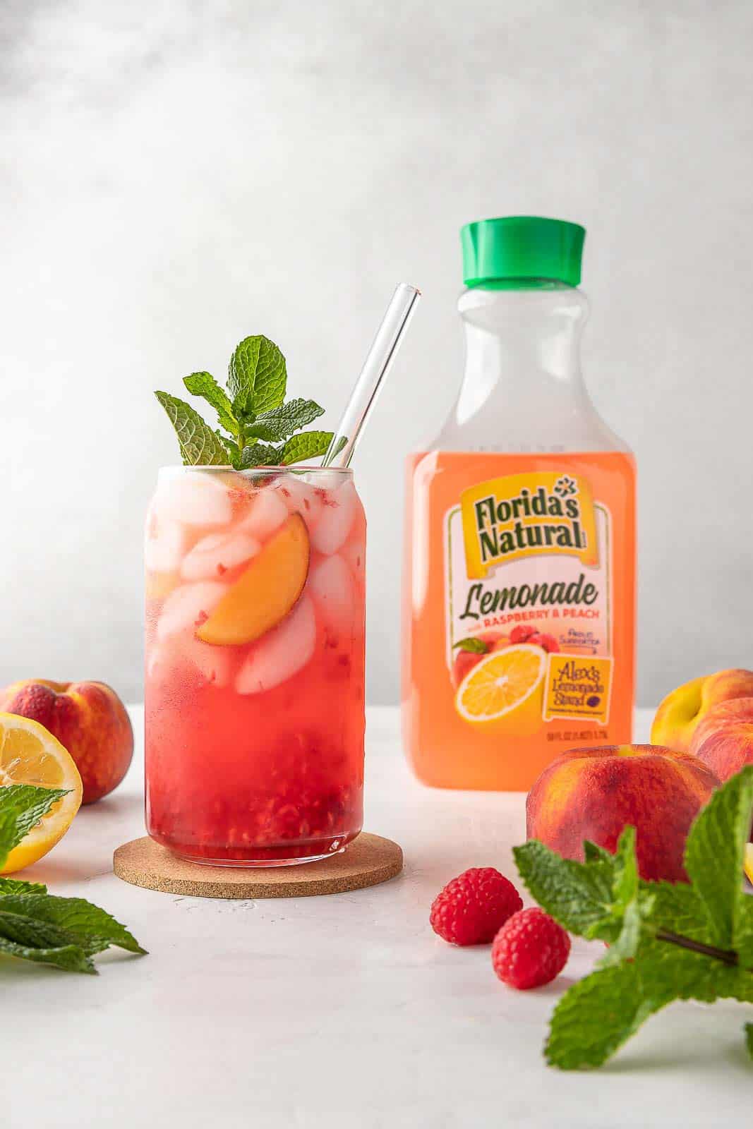 raspberry peach lemonade in a cup with a bottle of lemonade in the background