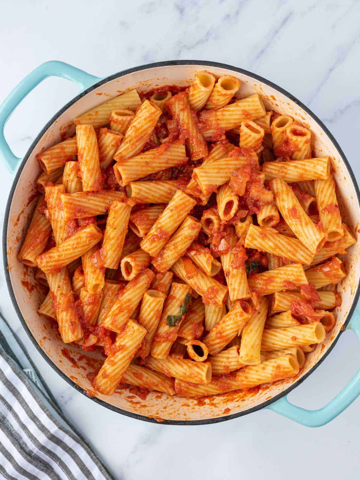 Combining sauce with the rigatoni pasta.