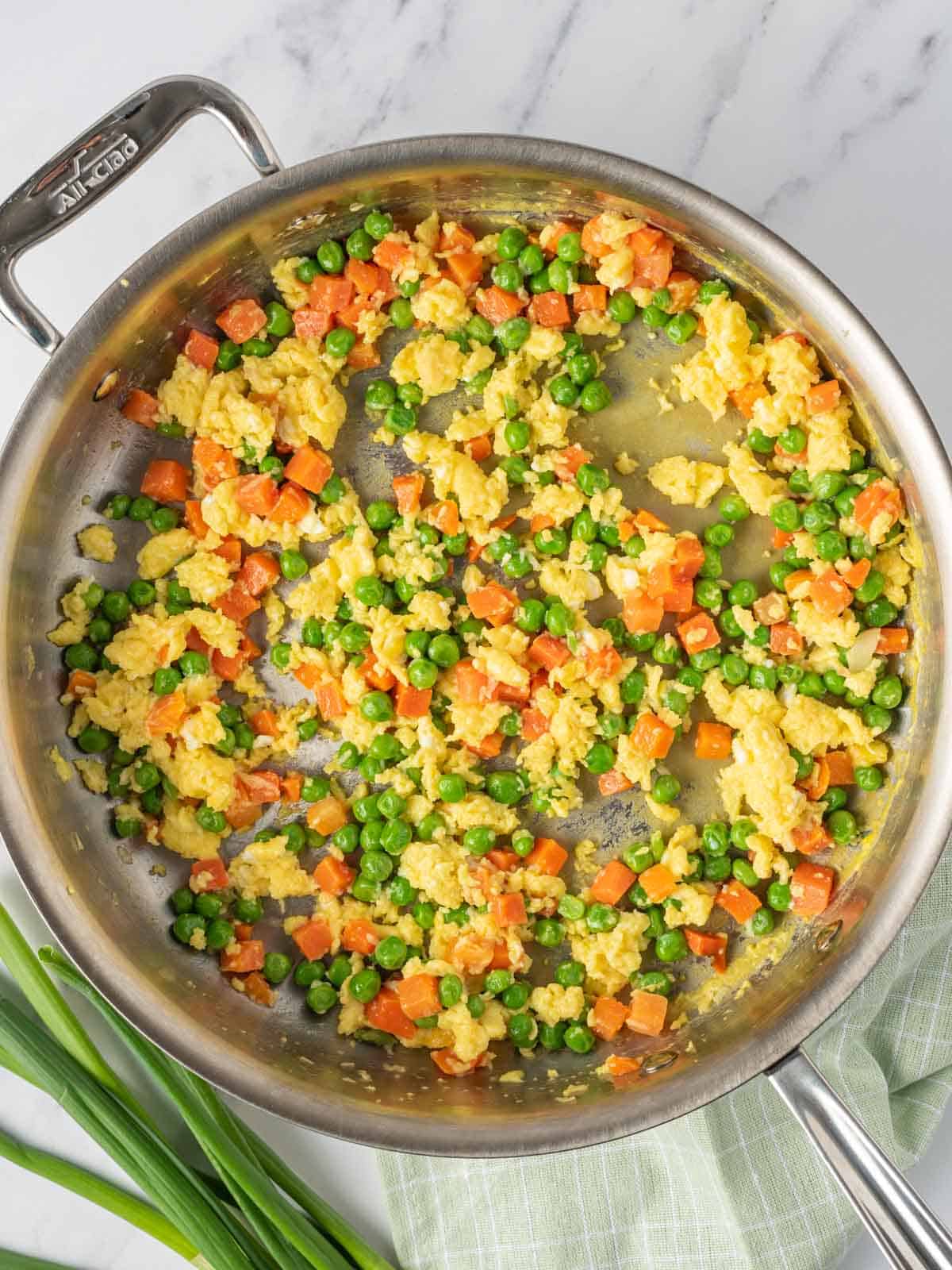 Process of cooking eggs and veggies for Chinese vegetarian fried rice.