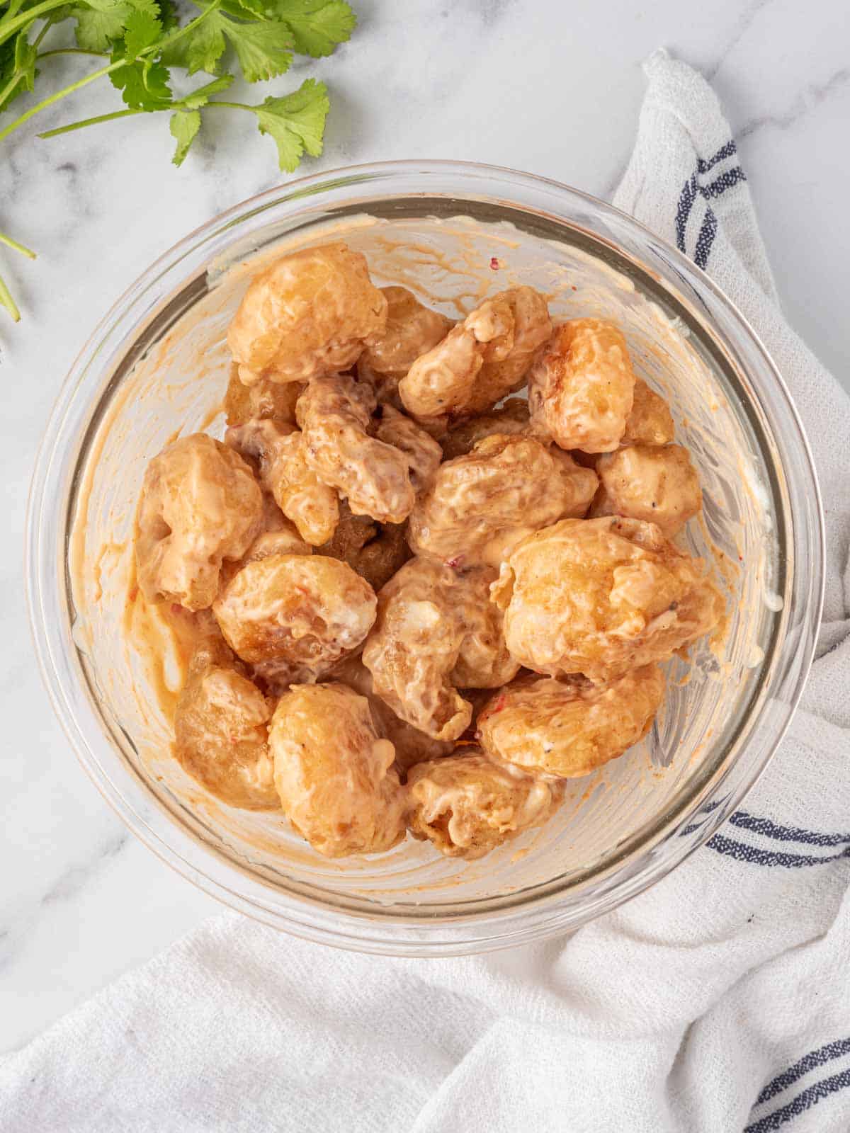 Coating fried shrimp with spicy dynamite shrimp sauce.