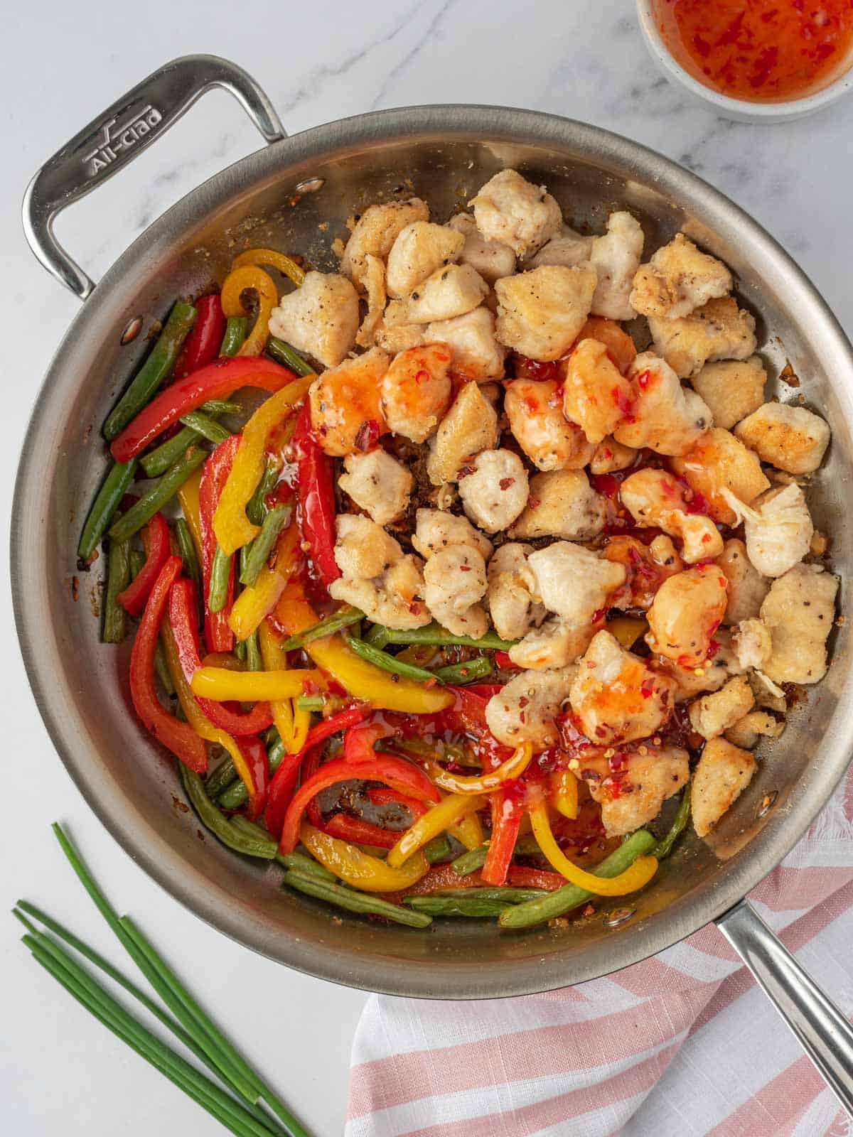 Combining sweet thai chili chicken stir fry in a skillet.