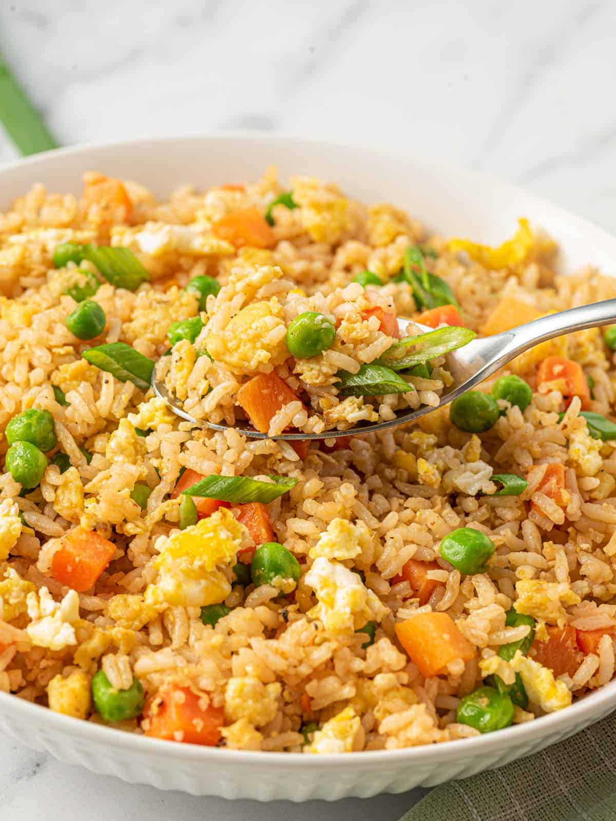 A spoon full of Chinese vegetarian fried rice over a bowl.