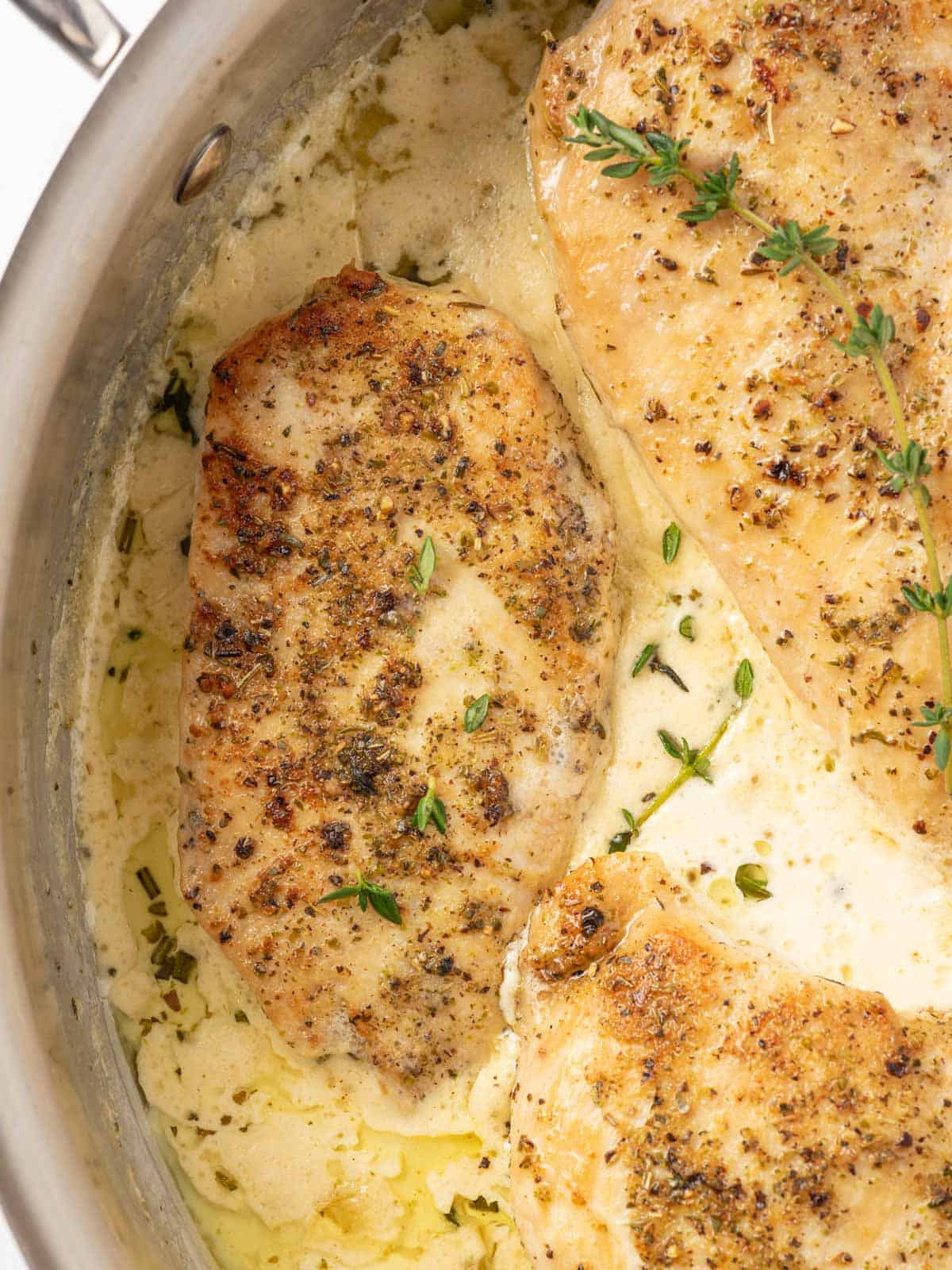 Close up of creamy garlic herb chicken in a skillet.