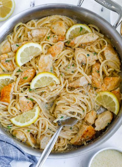 Lemon cream chicken pasta in a skillet with a fork.