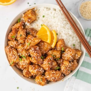 A bowl of crispy chicken in air fryer served with rice and chopsticks.