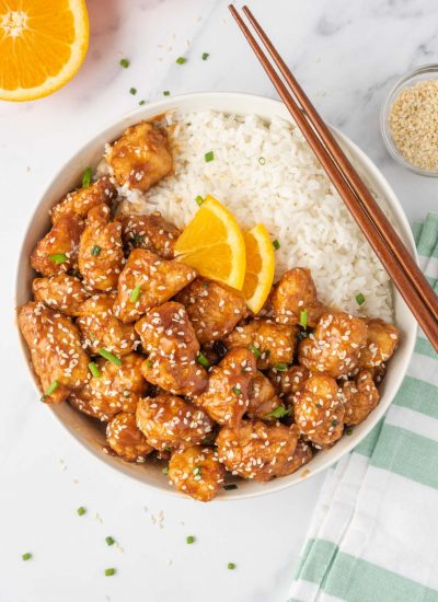 A bowl of crispy chicken in air fryer served with rice and chopsticks.