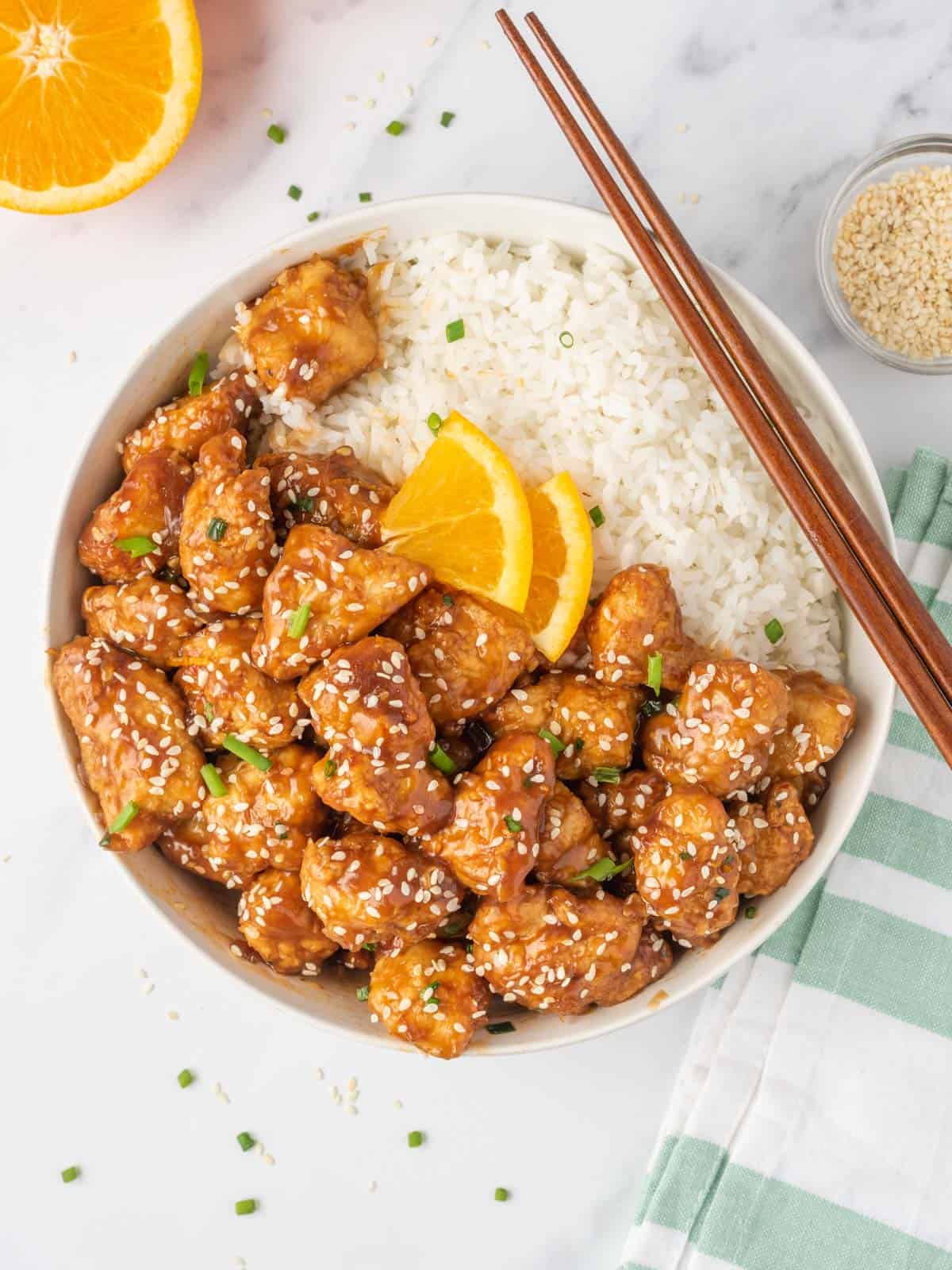 A bowl of crispy chicken in air fryer served with rice and chopsticks.