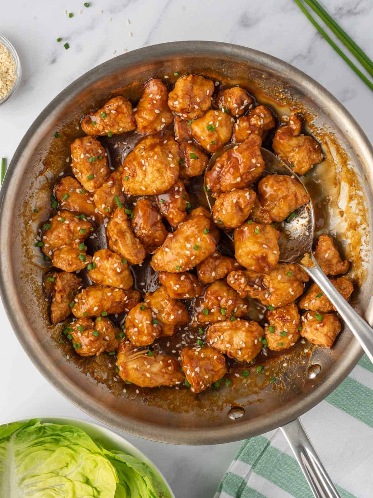 Air fryer orange chicken in a skillet with a serving spoon.