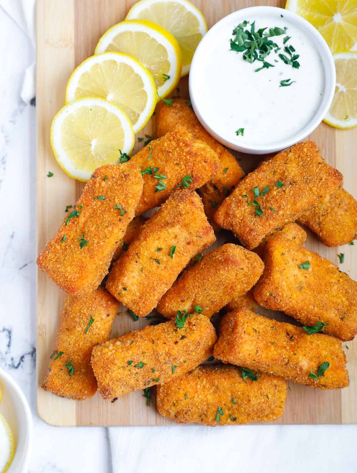 Panko baked salmon fingers on a board.